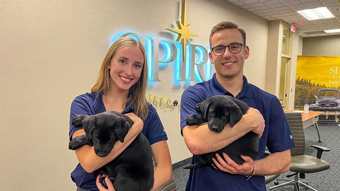 two SPIRE interns holding puppies from Second Handhounds